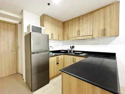 a kitchen with a stainless steel refrigerator and wooden cabinets at Spacious 2BR Living Rm Shore Res near NAIA MOA in Manila