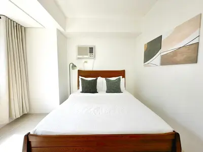 a bedroom with a bed with white sheets at Spacious 2BR Living Rm Shore Res near NAIA MOA in Manila