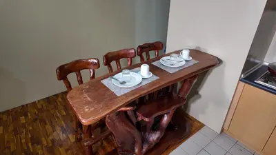 a wooden table with four chairs and cups and saucers at Monitor Gear Residences in Manila