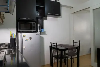 a kitchen with a refrigerator and a table with chairs at Monitor Gear Residences in Manila