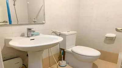 a bathroom with a white toilet and a sink at Monitor Gear Residences in Manila