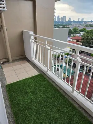 a balcony with a white railing and green grass at Minimalist stay in Satori Residences Pasig City in Manila