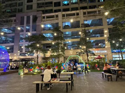 a group of people sitting on benches in front of a building at 55-SQM 1-BR golf club view condo in Central BGC in Manila