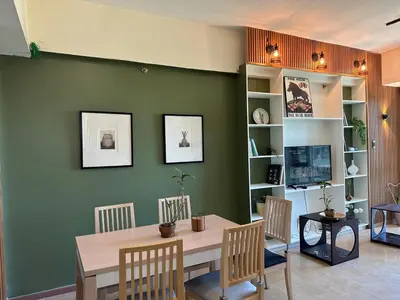 a dining room with a table and chairs and a green wall at 55-SQM 1-BR golf club view condo in Central BGC in Manila