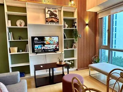 a living room with a television and a table and chairs at 55-SQM 1-BR golf club view condo in Central BGC in Manila