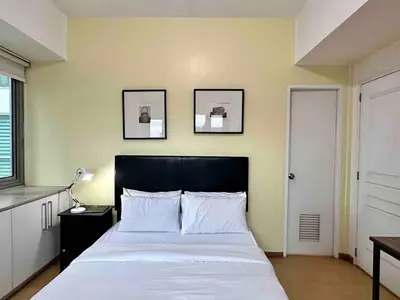 a bedroom with a bed and two pictures on the wall at 55-SQM 1-BR golf club view condo in Central BGC in Manila