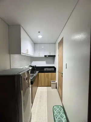 a small kitchen with white cabinets and a refrigerator at Bloom Residence by SMDC in Manila