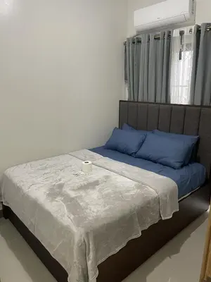 a bed with blue pillows and a candle on it at Bloom Residence by SMDC in Manila