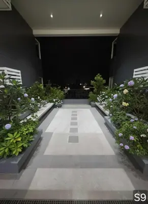 a walkway at night with flowers and plants at S-Line - Your place, your comfort! in Manila