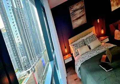 a bedroom with a bed and a large window at Explore Mitsukoshi BGC with pool and wifi in Manila