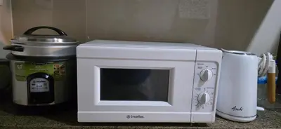 a white microwave sitting next to a coffee maker at Explore Mitsukoshi BGC with pool and wifi in Manila