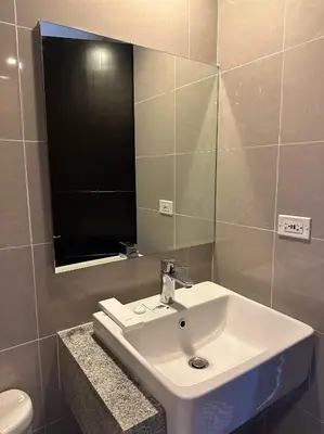a bathroom with a white sink and a mirror at Cozy 1-Bedroom in Uptown Parksuites BGC in Manila