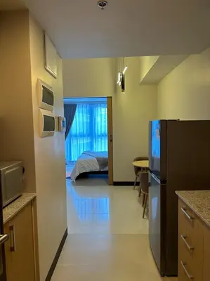 a kitchen with a refrigerator and a bedroom with a bed at Cozy 1-Bedroom in Uptown Parksuites BGC in Manila