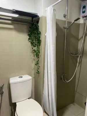 a bathroom with a toilet and a shower with a plant at Maria Solace in Manila