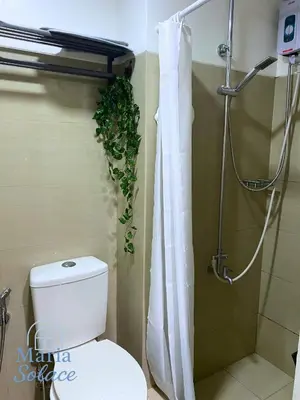 a bathroom with a toilet and a shower with a plant at Maria Solace in Manila