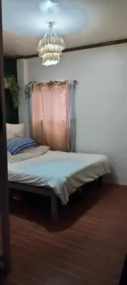a bed in a bedroom with a chandelier at Vacation Home by Rowena Sacarez in Trece Martires