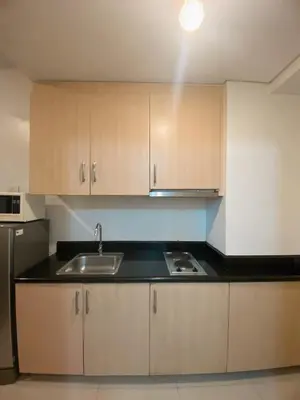a kitchen with wooden cabinets and a sink at Light Residence Condo with Balcony and Pool View in Manila