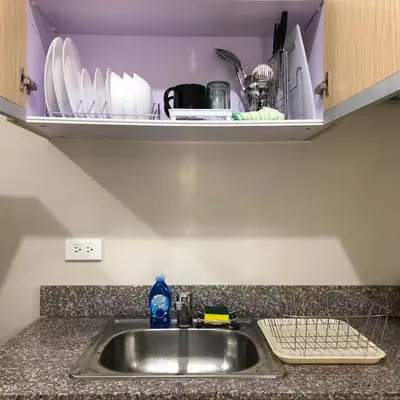a kitchen counter with a sink and a shelf with dishes at 1 BR Taytay HIVE Condo WIFI Netflix Pool Patio in Taytay