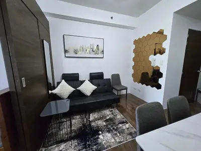 a living room with a black couch and a table at The Air Residences Makati in Manila