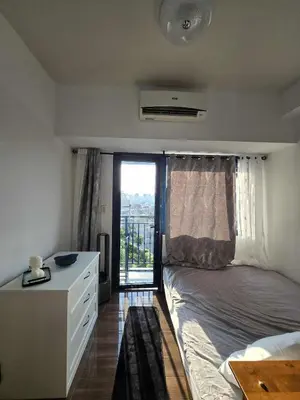 a bedroom with a bed and a dresser and a window at The Air Residences Makati in Manila