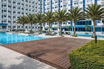 a large pool with palm trees in front of a building at 1 BR Makati JAZZ Condo WIFI Netflix Pool Balcony in Manila