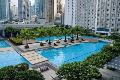 an overhead view of a large pool with palm trees and buildings at 1 BR Makati JAZZ Condo WIFI Netflix Pool Balcony in Manila