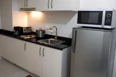 a kitchen with a sink and a microwave and a refrigerator at 1 BR Makati JAZZ Condo WIFI Netflix Pool Balcony in Manila