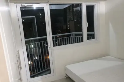 a room with two windows with a bed and a balcony at 1 BR Makati JAZZ Condo WIFI Netflix Pool Balcony in Manila