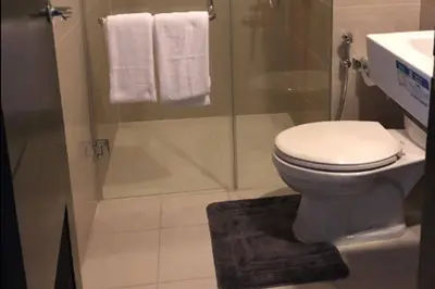 a bathroom with a toilet and a shower with towels at 81 Newport Boulevard across NAIA T3 Airport in Manila