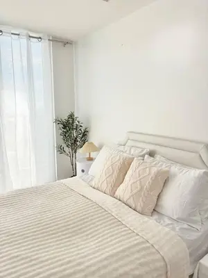 a white bedroom with a large bed with white sheets at Playa Delea Minimalist Azure 1BR Pool Beach Staycation in Manila
