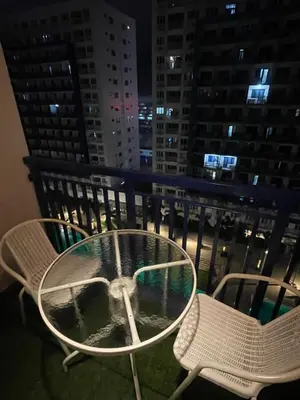 a table and chairs on a balcony at night at Premiere Haven MOA Staycation in Manila