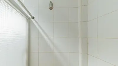 a shower with a white tiled wall at Urban Travellers Hotel by RedDoorz in Manila