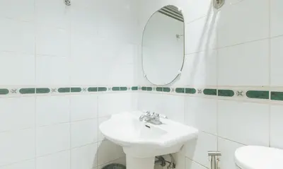 a white bathroom with a sink and a mirror at Urban Travellers Hotel by RedDoorz in Manila