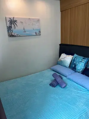 a bed with blue sheets and pillows on it at MOA Staycation Condotel PASAY in Manila