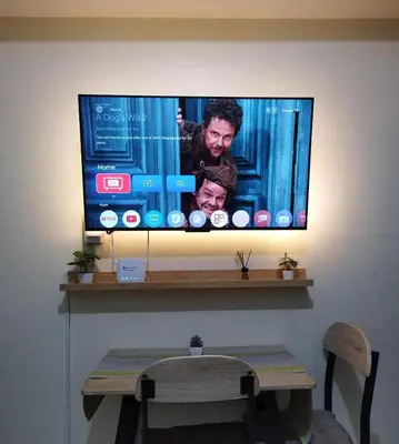 a flat screen tv on a wall with a table at 25mins from NAIA1 in Manila