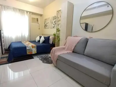 a living room with a couch and a bed and a mirror at 25mins from NAIA1 in Manila