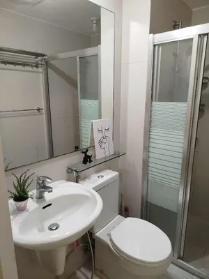 a white bathroom with a toilet and a sink at Azure Staycation with Pool View, Wifi and Netflix in Manila