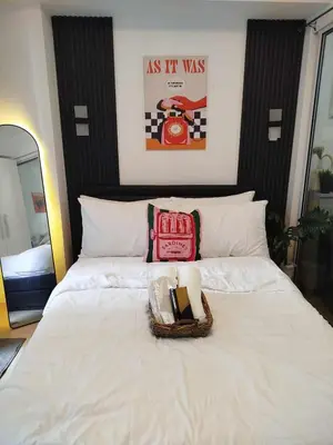 a bedroom with a white bed with a basket on it at Azure Staycation with Pool View, Wifi and Netflix in Manila