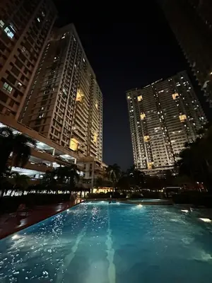 a large swimming pool in a city at night at Resort-style oasis at the the heart of the city in Manila