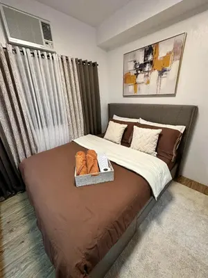 a bedroom with a bed with a tray of shoes on it at Studio City Staycation in Alabang in Manila