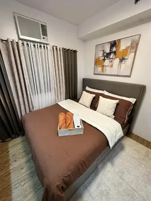 a bedroom with a bed with a tray of shoes on it at Studio City Staycation in Alabang in Manila
