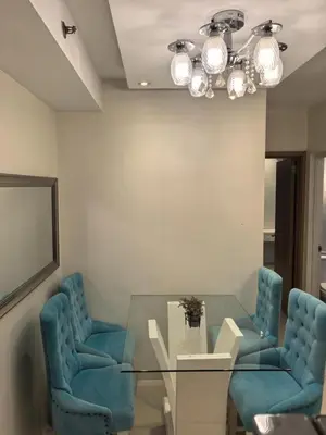 a dining room with a glass table and two blue chairs at 2 BEDROOM SHELL RESIDENCES MOA view in Manila