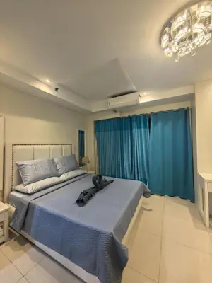 a bedroom with a large bed with blue curtains at 2 BEDROOM SHELL RESIDENCES MOA view in Manila