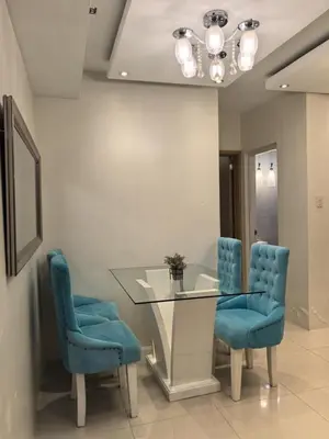 a dining room with a glass table and blue chairs at 2 BEDROOM SHELL RESIDENCES MOA view in Manila
