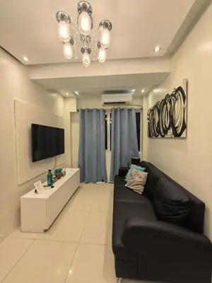 a living room with a black couch and a tv at 2 BEDROOM SHELL RESIDENCES MOA view in Manila