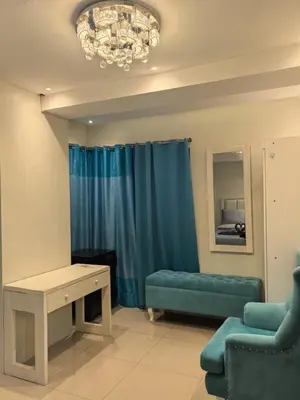 a living room with a blue couch and a table at 2 BEDROOM SHELL RESIDENCES MOA view in Manila