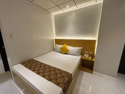 a small bedroom with a bed and a yellow pillow at LuxeLite Suites Pasay in Pasay