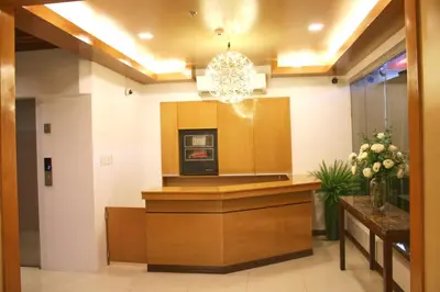 a hotel lobby with a reception desk and a chandelier at LuxeLite Suites Pasay in Pasay