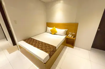 a small room with a bed and a night stand at LuxeLite Suites Pasay in Pasay