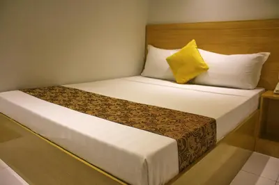a hotel room with a bed with a yellow pillow at LuxeLite Suites Pasay in Pasay